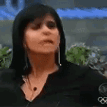 a woman with long black hair is wearing a black shirt with the olympics logo on the sleeve .