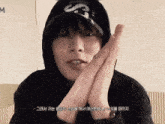a person wearing a hoodie and a hat with the letter m on it