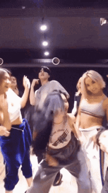 a group of people are dancing in a room and one of them is wearing a shirt that says ' guns '