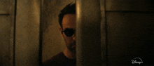 a man wearing sunglasses is behind a door that says disney on it
