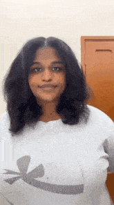a woman is wearing a white shirt with a black letter k on it