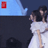 a woman in a white dress stands next to another woman in front of a screen that says cct 48