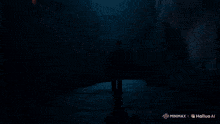a man in a suit is walking down a dark alleyway with a fireball coming out of his mouth behind him