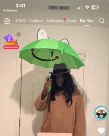 a man holding a green umbrella with a smiley face on it in front of a door that says summer picnic