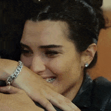 a woman wearing a bracelet on her wrist is smiling and hugging another woman
