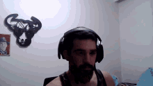 a man wearing headphones has a picture of a man in a hat on the wall