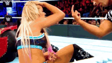 a female wrestler is sitting on the ground while a referee looks on .