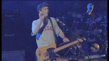 a man wearing a vassa shirt playing a guitar