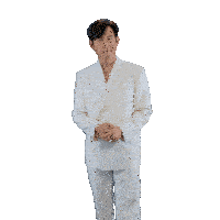 a man in a white suit is pointing at his ears
