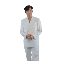 a man in a white suit is pointing at his ears