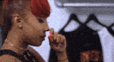 a woman with red hair is applying nail polish to her nails in a closet .