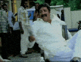 a man with a mustache is sitting in a chair and making a peace sign
