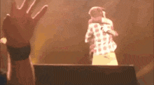 a man in a plaid shirt is hugging another man on stage