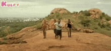 a group of men are running down a dirt road on top of a hill .