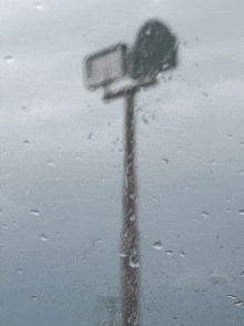 a street sign is visible through a window with rain drops