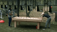 two men are playing pool on a table outside