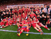 a group of soccer players are posing for a photo with a trophy
