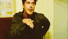 a man in a leather jacket is making a gesture with his hands .