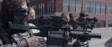 a man wearing a mask is holding a rifle in front of a building .