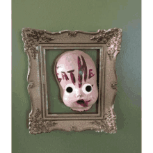 a framed picture of a doll with the words eat me written on its face