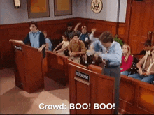 a group of people are sitting in a courtroom and a man is standing in front of the defendant .