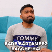 a man with a tommy shirt on is sitting on a couch