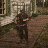 a man in a hat is standing on a wooden walkway in front of a house with a sign that says " welcome "