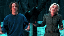 a man in a blue sweater stands next to a woman in a black jacket