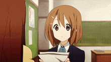 a girl with brown hair is holding a piece of paper in her hand