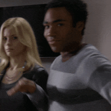 a man and a woman are standing next to each other and the man is wearing a striped sweater