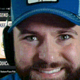 a man with a beard wearing a blue hat and headphones smiles
