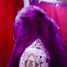 a woman with purple hair is wearing a white top