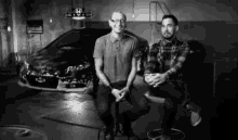 two men are sitting in front of a honda car
