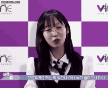 a woman wearing glasses and a tie stands in front of a purple and white checkered backdrop with the word vine on it