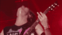 a man playing a guitar with a shirt that says ' land ' on it