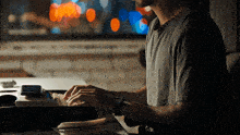 a man in a gray shirt is typing on a keyboard