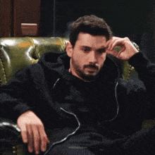 a man with his eyes closed is sitting on a green leather chair