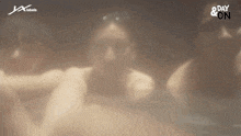 a group of people are sitting in a hot tub with a day & on logo in the background