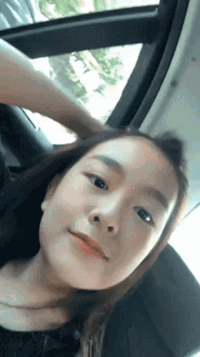 a young girl is sitting in a car with her hand on her head