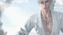 a man wearing a white shirt and a necklace is standing in front of a blue sky .