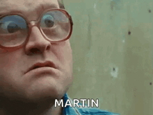 a man wearing glasses and a blue shirt is making a funny face and says martin .