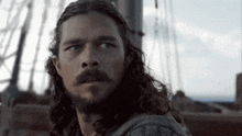 a man with long hair and a beard is looking at the camera
