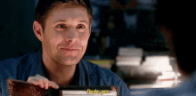 a man is smiling while holding a notebook that says `` dude yes '' .
