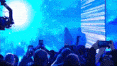 a crowd of people holding their phones up in front of a blue screen