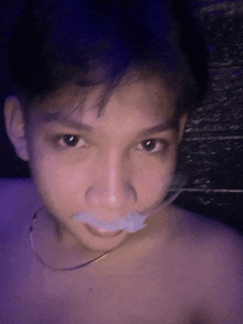 a young man without a shirt has a piece of tape in his mouth