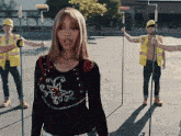 a woman in a black shirt is surrounded by construction workers