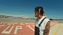 a man with dreadlocks stands on a runway with a stop sign on it