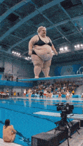a woman in a bikini is standing on a diving board in a pool