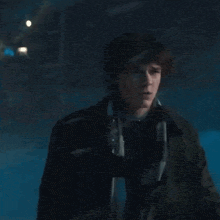 a young man wearing a scarf and a jacket is standing in the snow .
