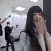 a woman covering her face with her hands while a man takes a picture of her
